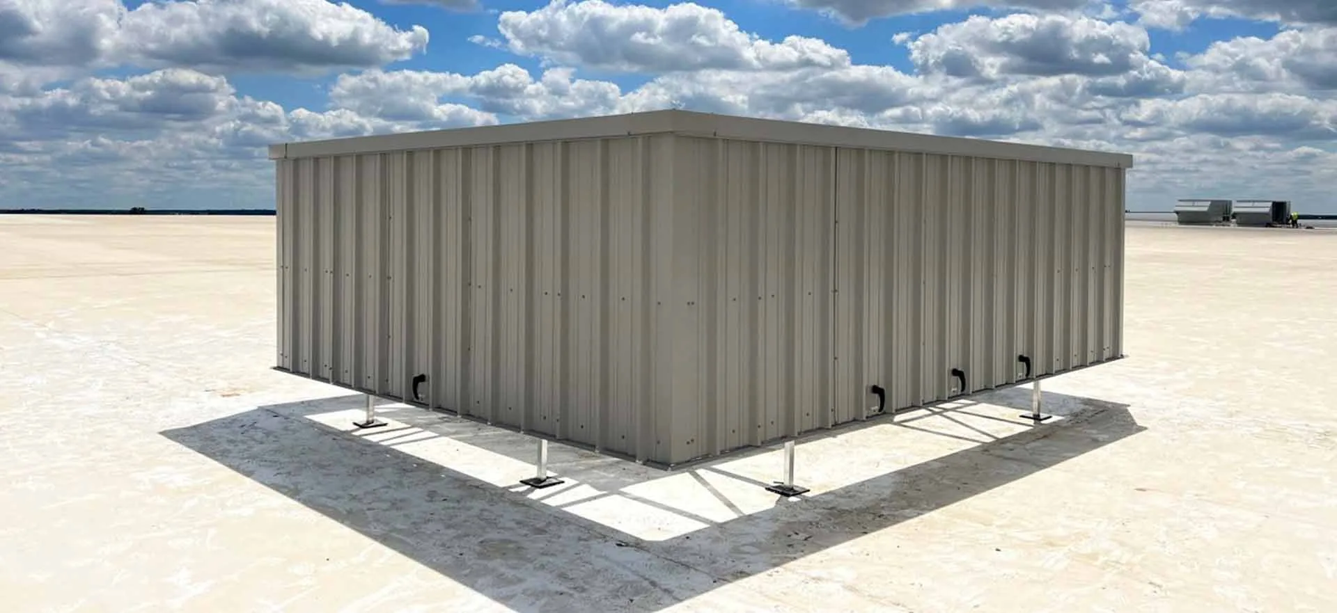 Wide beige steel RTU screen elevated on a commercial rooftop