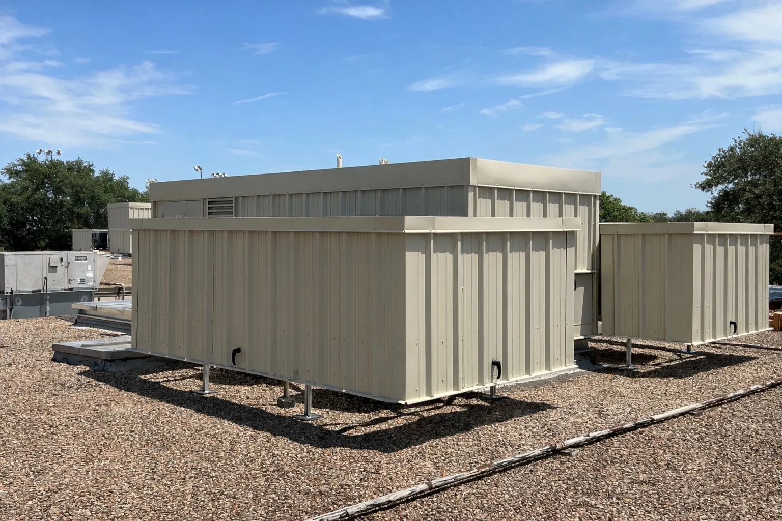 Cluster of beige steel RTU screens on a gravel commercial rooftop